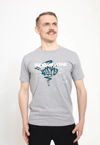 Šedé bavlněné tričko s kulatým výstřihem, krátkými rukávy a grafickým potiskem v bílé a azurové barvě, zobrazující text "WORKERWEAR" a abstraktní design.