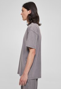 Tricou oversized gri din material moale. Are mâneci scurte, guler rotund și detalii de cusătură vizibile. Design simplu cu o croială lejeră.