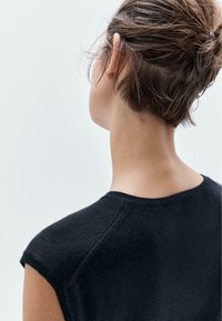 Black knitted sweater with a crew neck and cap sleeves, featuring a soft texture. The back view shows a clean neckline and subtle shoulder seams.