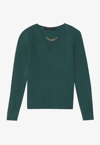 Pull en maille côtelée à manches longues de couleur vert foncé avec un col en V et une courte chaîne dorée décorative sous le col.