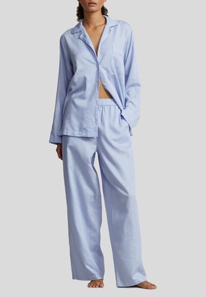 Light blue, satin pajama set featuring a button-up shirt with a pocket and loose-fitting pants with an elastic waistband and subtle patterns.