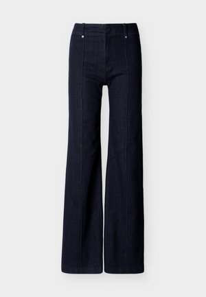 Σκούρο μπλε τζιν παντελόνι με φαρδύ πόδι, ψηλή μέση και κάθετες ραφές μπροστά σε λευκό φόντο.