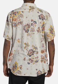 Lyhythihainen paita, valkoinen, jossa värikkäät kukka- ja timanttikuvioinnit, kevyt kangas, rento istuvuus, napillinen kaulus, hienovarainen tekstuuri.