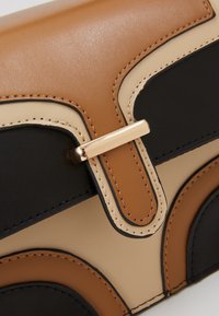 Kožená psaníčko s geometrickým vzorem, které obsahuje hnědé, béžové a černé panely. Hladký povrch s detaily v zlaté barvě a švy.