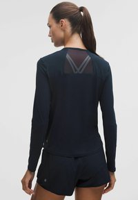 Granatowa, długosleeve'owa koszulka sportowa z siateczkowym tyłem i kontrastowymi, ukośnymi akcentami. Charakteryzuje się gładkim materiałem i dopasowanym krojem.