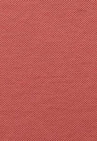 Strukturierter Stoffmuster in einem gedämpften Korallton, mit einem gewebten Muster, das eine leicht raue Oberfläche und ein einheitliches Erscheinungsbild aufweist.