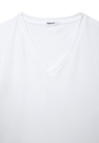 Hvid v-hals t-shirt lavet af blødt bomuld med en glat tekstur. Etiketten ved halsen siger "Filippa K." Enkel, ren design uden udsmykninger.