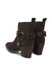 Botas de tobillo de ante marrón con un tacón cuadrado, que presentan una hebilla metálica y acentos decorativos en el lado para un detalle adicional.