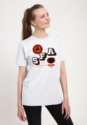 Ung kvinde med hestehale iført en hvid Starfleet Academy T-shirt med orange og sort logo og tekst, der ser let opad.