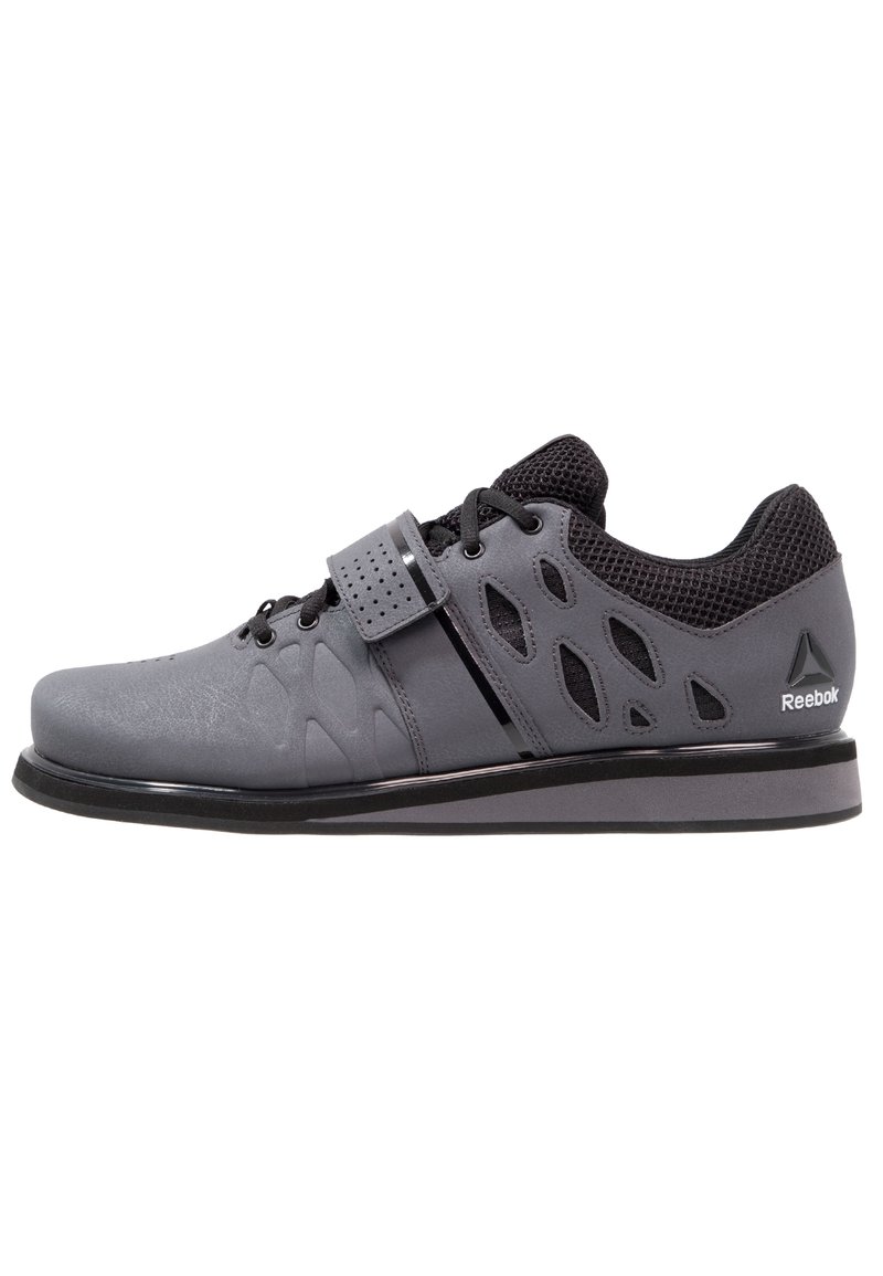 Gray athletic shoe with a smooth texture, mesh upper, and cut-out details. Features a Velcro strap and black accents on the sole and heel.