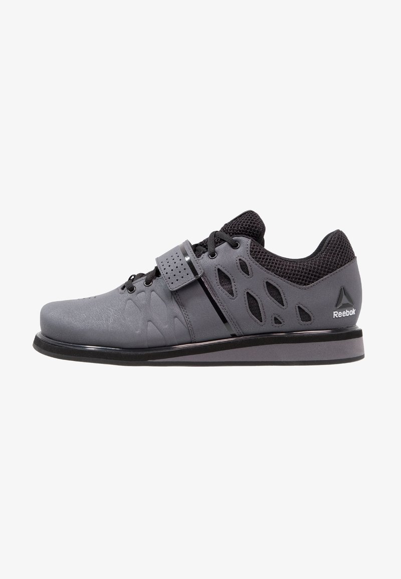 Gray athletic shoe with a smooth texture, mesh upper, and cut-out details. Features a Velcro strap and black accents on the sole and heel.