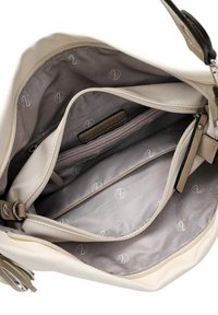Beige handbag with multiple compartments, soft texture, and a patterned gray interior featuring a zippered pocket and a brand label.