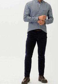 Rutigt knäppskjorta i blått, svart och vitt; mörk marinblå kordbyxor; bruna läderstövlar; figurnära passform. Inga andra detaljer finns.