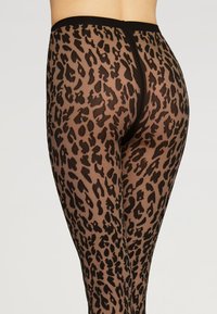 Gennemsigtige sorte strømpebukser med leopardprint, der har en glat tekstur, strækbar talje og fremhæver kroppens konturer.