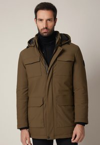 Brązowa ocieplana parka z kapturem, czterema kieszeniami z przodu i zapięciem na zamek. Wykonana z gładkiego materiału o matowym wykończeniu.