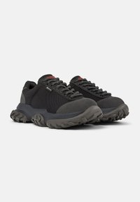 Czarne buty trekkingowe o teksturowanej powierzchni i grubych gumowych podeszwach, z wyraźnymi sznurówkami oraz z etykietą wodoodporną z boku.