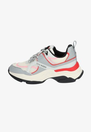 Sneaker gris avec des panneaux en maille et des accents rouge vif. Design arrondi, semelle texturée et système de laçage distinctif. Nom de la marque visible.