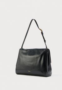 Must nahast Furla õlakott ühe reguleeritava rihmaga ja minimalistliku kuldse logoga ees, ühtlase taustaga.