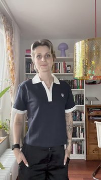 Mornarska polo majica z belim ovratnikom in manšeti, z vezenim logotipom na levi strani prsnega koša. Kratke rokave, bombažni material, sproščen kroj.