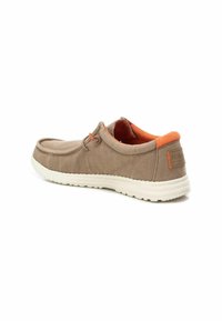 Zapato de lona marrón con suela de goma blanca, acentos naranjas en el talón y el interior, y un diseño de cordones simple. Punta redonda y estilo bajo.