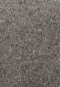 Eri tekstuuriga kootud kangas erinevates hallides toonides, millel on pruunide ja kreemjate laikude nüansid, luues pehme ja koduse mulje.