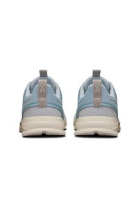 Baskets de sport bleu clair avec une tige en mesh, accents beiges contrastés et un talon rembourré. Présente une semelle texturée pour une meilleure adhérence.