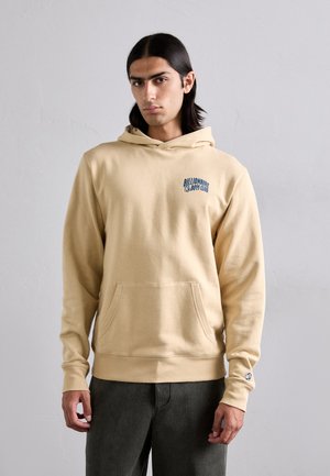 Beige hoodie with a kangaroo pocket, features a blue embroidered logo on the chest, and ribbed cuffs at the sleeves and hem.