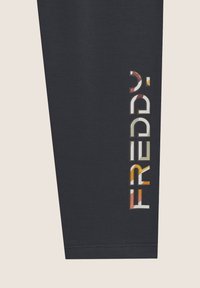 Leggings negros con un diseño ajustado, que presentan un colorido logo "FREDDY" en el lateral. Fabricados con un material suave y de textura lisa.
