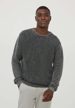 Maglione a righe bianche e nere con scollo rotondo, maniche lunghe e texture a costine. Il tessuto morbido si adatta comodamente al corpo.