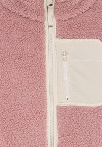 Rosa fleece-jakke med kremfarget glidelås og glidelåslomme på brystet med teksten "Eventyret Venter".