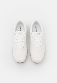 Vita sneakers med en strukturerad ovandel, rund tå och platta snören. Innersulan visar "ANNA FIELD"-logotypen. Svart gummisula.