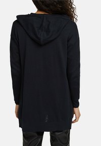 Long-sleeve navy hoodie, soft knit material, relaxed fit, features a drawstring hood, and ribbed cuffs and hem. Smooth texture with no patterns.