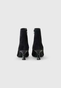 Sorte semsko ankle boots i svart nubuck med glidelås og utvidet hæl. Jevn tekstur, tettsittende design og minimalistisk stil.