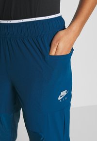 Nike AIR Sporthosen in Dunkelblau, ausgestattet mit einem elastischen Bund, seitlicher Tasche und Logo-Detail in Weiß am unteren Bein.