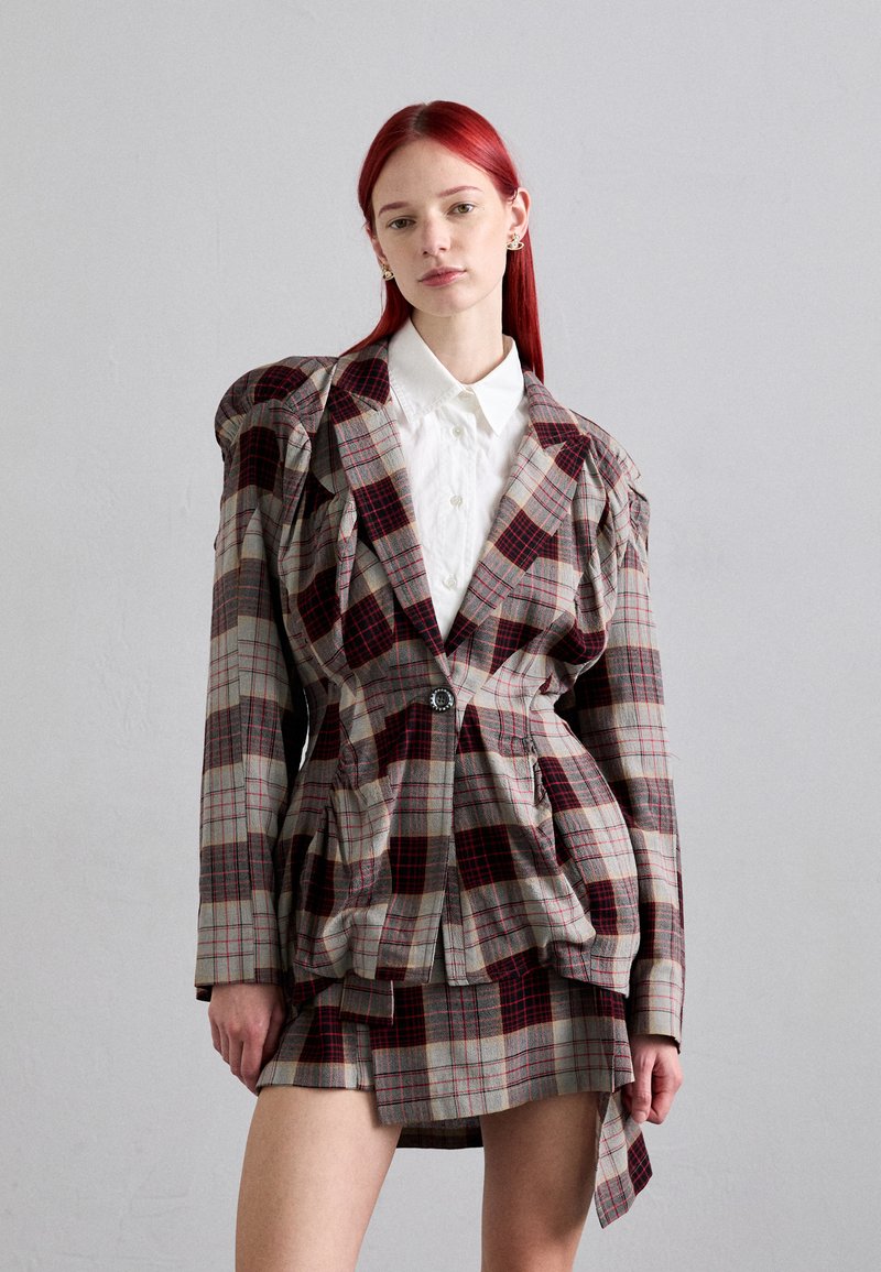 Blazer a cuadros con hombros abullonados, en colores beige, rojo y gris oscuro, cierre de un solo botón, combinado con una falda mini a juego.
