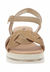 Sandal beige con una toma texture e accenti metallici, una cinghietta regolabile alla caviglia e una suola imbottita con una piattaforma bianca.