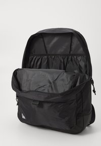 Zaino nero realizzato in tessuto testurizzato, con un compartimento principale con zip, una tasca frontale aggiuntiva e spallacci regolabili.