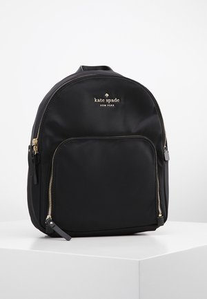 Czarny plecak Kate Spade New York ze złotymi zamkami błyskawicznymi i przednią kieszenią na zamek, prezentowany na białej powierzchni na jednolitym tle.