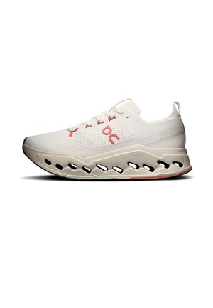 Hellbeiger Laufschuh mit rotem Logo, atmungsaktivem Mesh-Obermaterial und dicker Sohle mit schwarzen ovalen Aussparungen für Dämpfung und Unterstützung.