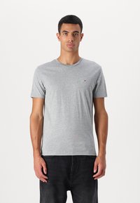 Tricou gri cu mânecă scurtă, cu guler rotund și un mic logo brodat pe piept. Fabricat din material moale din bumbac.