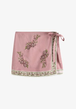 Pink fabric apron with floral embroidery, featuring green accents and a striped border. Ties at the waist with a decorative bow.