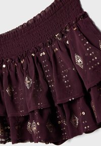 Mørke lilla lagdelt nederdel med smøget taljebånd og guldfarvede palietdiamantmønstre på let stof.