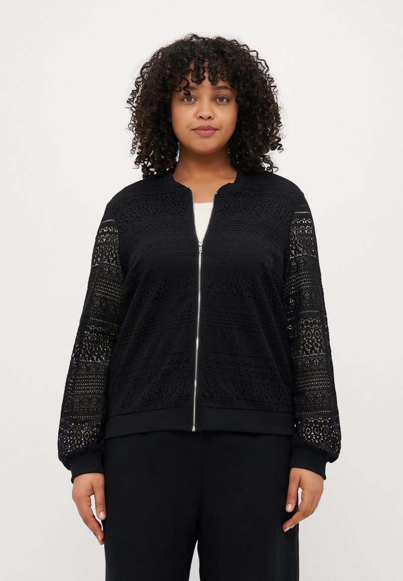 Veste bombers noire avec des détails en dentelle complexe sur les manches. Comprend une fermeture éclair à l'avant, des poignets côtelés et un design de corps texturé.