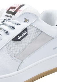 White sneakers featuring a leather upper, mesh panels, a gray suede accent, textured laces, and a black logo patch. Rubber sole with a low profile.