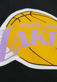 Schwarzer Stoff mit einem großen gelben Basketball-Motiv und lila Text, der "LOS ANGELES LAKERS" liest. Bold-Design mit glatter Textur.