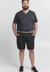 Svarte cargo-shorts med sidelommer, kombinert med en mørkegrå henley-skjorte med to knapper. Brukt med et stripete belte og svarte joggesko.