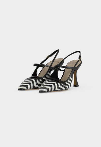 Escarpins à talons hauts slingback noir et blanc à motif zigzag, bouts pointus et fines brides de cheville avec boucles dorées.