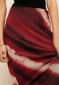 Batik-Maxi-Rock in Burgunder- und Beigetönen, mit glatter Textur und drapierter Gestaltung sowie asymmetrischem Saum.