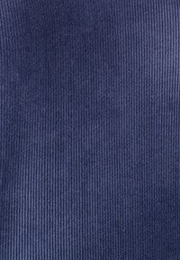 Tela de pana azul marino con costillas verticales, que presenta una textura suave y un patrón uniforme, adecuada para aplicaciones en ropa o tapicería.