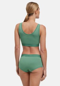 Grüner Sport-BH aus Baumwollmischung und passende Hipster-Shorts mit glatter Textur, breiten Trägern und elastischen Bund.